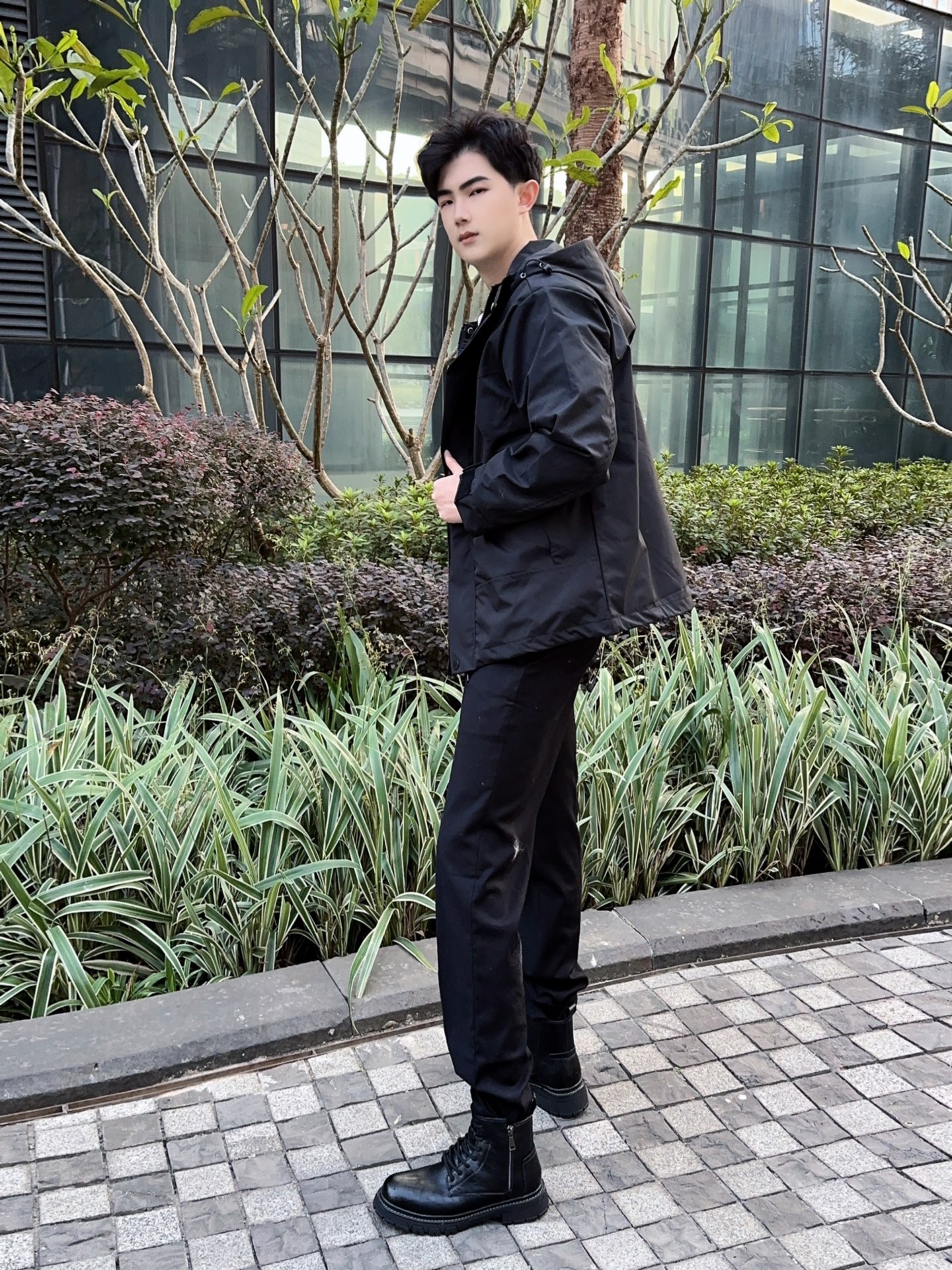 黑色冲锋衣外套内搭白色t恤 下身休闲裤搭配一双复古加绒的马丁靴 这